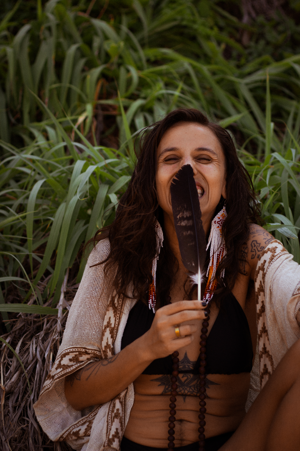 René holding a feather in lush greenery, eyes closed in joyful presence